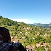 Pogled sa visine iz ulaznog portala Potpecke pecine na selo Potpece u dolini okruzeno zelenim brdima