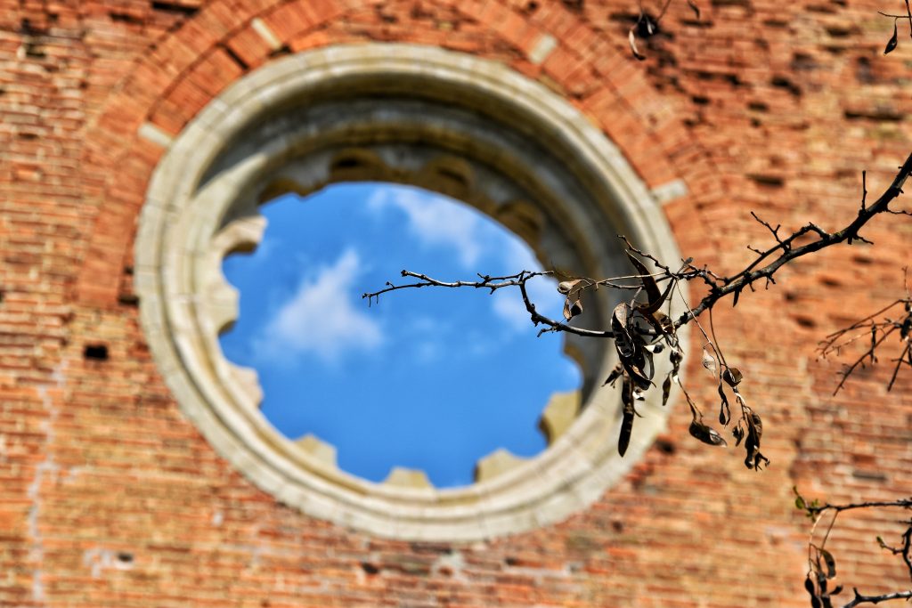 Rekonstruisana kamena rozeta na zidu od crvene opeke crkve Araca sa pogledom na plavo nebo i oblake