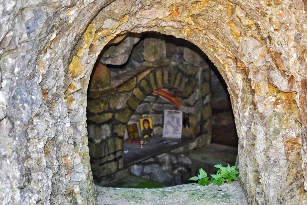 Pogled kroz kameni otvor na unutrašnjost pećinske crkve Kađenica sa vidljivim ikonama i oltarom