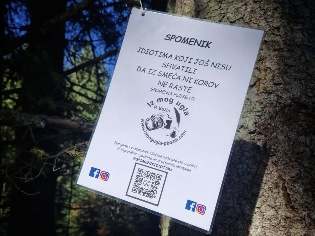 Beli natpis sa porukom 'Spomenik idiotima koji još nisu shvatili da iz smeća ni korov ne raste' prikačen na stablo drveta u šumi na Tari. Natpis je deo ekološke inicijative i ima QR kod za sajt.