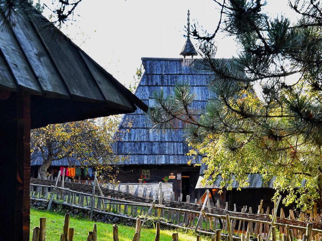 Etno muzej Staro selo Sirogojno brvnara sa visokim drvenim krovom i sarenom vunom na suncu
