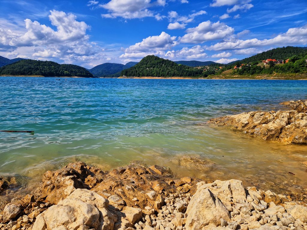 Krupni plan kristalno čiste tirkizne vode jezera Zaovine sa stenovitom obalom u prvom planu