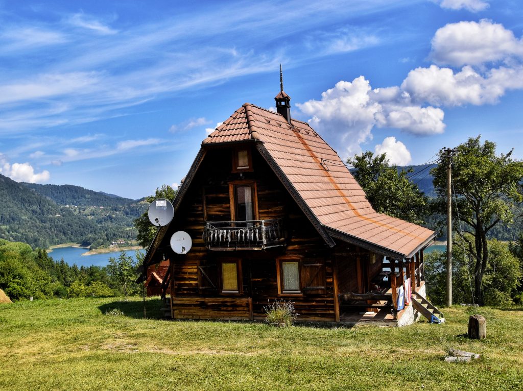 Tradicionalna drvena brvnara Konaci Zaovljanska jezera na planini Tari sa pogledom na jezero u pozadini