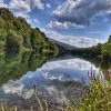 Bistra i mirna reka Drina kod Bajine Baste sa odrazom oblaka u vodi i zelenilom obale
