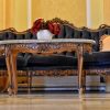 Stilska crna sofa sa rezbarenim drvenim ramom i mermerni stočić sa crvenim cvećem u enterijeru dvorca Fantast