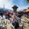 Žena sa golubovima ispred Sebilj česme na Baščaršiji u Sarajevu