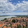 Panorama Zemuna sa crvenim krovovima kuca, crkvom i Dunavom u pozadini pod plavim nebom sa belim oblacima