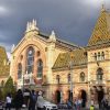 Velika centralna pijaca u Budimpesti sa prepoznatljivim sarenim krovom od keramike i ljudima koji prolaze ispred ulaza