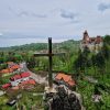 Pogled sa vidikovca na dvorac Bran u Rumuniji poznat kao dvorac grofa Drakule sa metalnim krstom u prvom planu