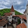Pogled na unutrašnje dvorište dvorca Bran u Rumuniji sa belim kulama, drvenim gredama i krovovima od biber crepa pod oblačnim nebom