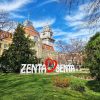 Pogled na monumentalnu žutu Gradsku kuću u Senti sa visokim tornjem, ispred koje se nalazi beli natpis Zenta-Senta sa crvenim srcem na zelenom travnjaku