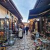 Uska ulica Kazandziluk na Bascarsiji u Sarajevu sa izlozenim bakarnim posudjem i turistima koji obilaze radnje