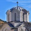 Kupola Kraljeve crkve u manastiru Studenica od belog kamena sa krstom pod plavim nebom