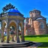 Manastir Zica kod Kraljeva sa karakteristicnom crvenom fasadom i kupolama okruzen zelenilom pod plavim nebom