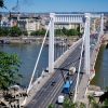 Beli viseci most Erzebet u Budimpesti sa saobracajem i panoramom grada u pozadini pod vedrim nebom