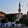 Islam-agina dzamija u centru Nisa sa belim minaretom i crvenim krovom okruzena drvoredom i gradskim zgradama u sumrak