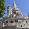 Kamene kule Ribarskog bastiona u Budimpesti sa stepenistem i ulicnim svetiljkama pod jasnim plavim nebom