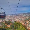 Pogled iz kabine sarajevske zicare na panoramu grada, crvene krovove kuca i okolna brda pod plavim nebom