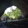 Pogled iz unutrasnjosti Stopica pecine ka monumentalnom ulazu, stazi za posetioce i zelenilu spoljasnjeg sveta