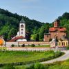 Kompleks manastira Lelic kod Valjeva sa crkvom od crvene cigle i zvonikom okruzen zelenim brdima i sumom pod plavim nebom