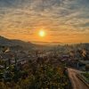 Panorama Sarajeva tokom zalaska sunca sa pogledom na stari grad, krovove kuca i okolna brda u zlatnom satu