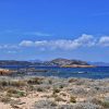 Divlja obala ostrva Tavolara u Sardiniji sa niskim rastinjem strmim stenama i plavim morem u pozadini
