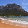 Ostrvo Tavolara u Sardiniji pogled sa pescane plaze na monumentalnu stenu i tirkizno more