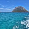 Monumentalna stena ostrva Tavolara u Sardiniji okruzena tirkiznim morem snimljena sa broda u pokretu